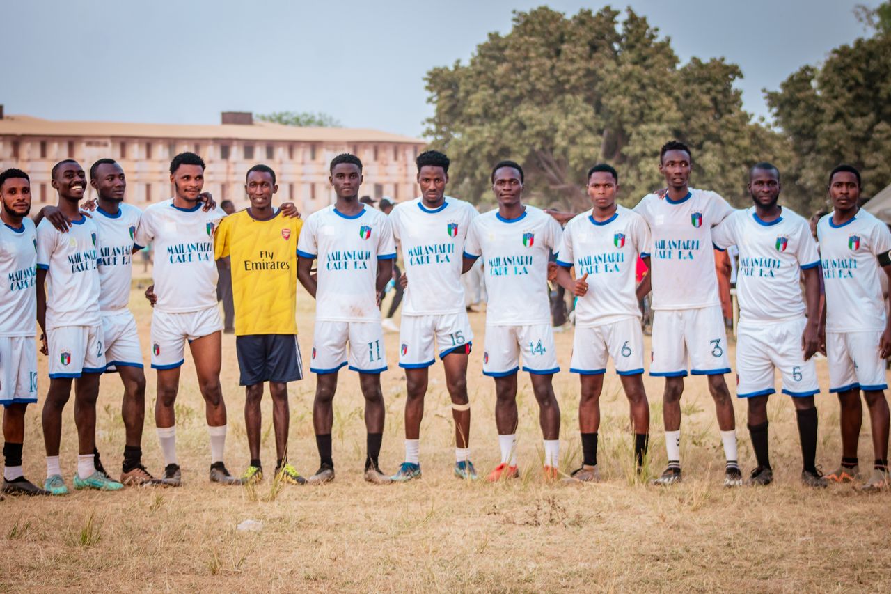 a diverse soccer team poses together outdoors on a field in a group ph