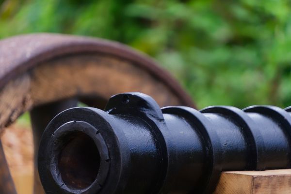 Gros plan d'un vieux fût de canon noir sur un affût à roue en bois
