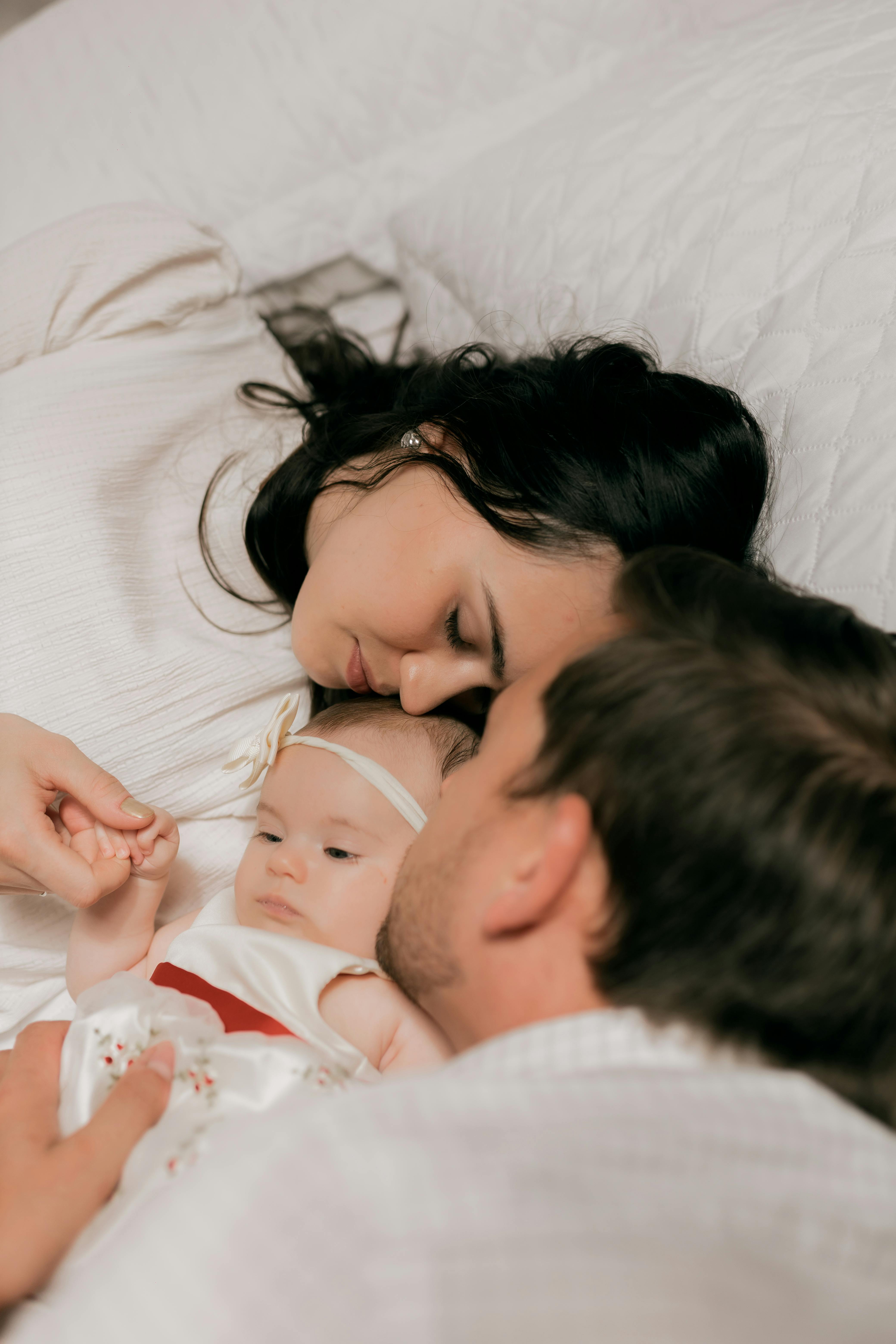A tender family scene with parents and their newborn baby sharing a quiet, loving moment indoors.