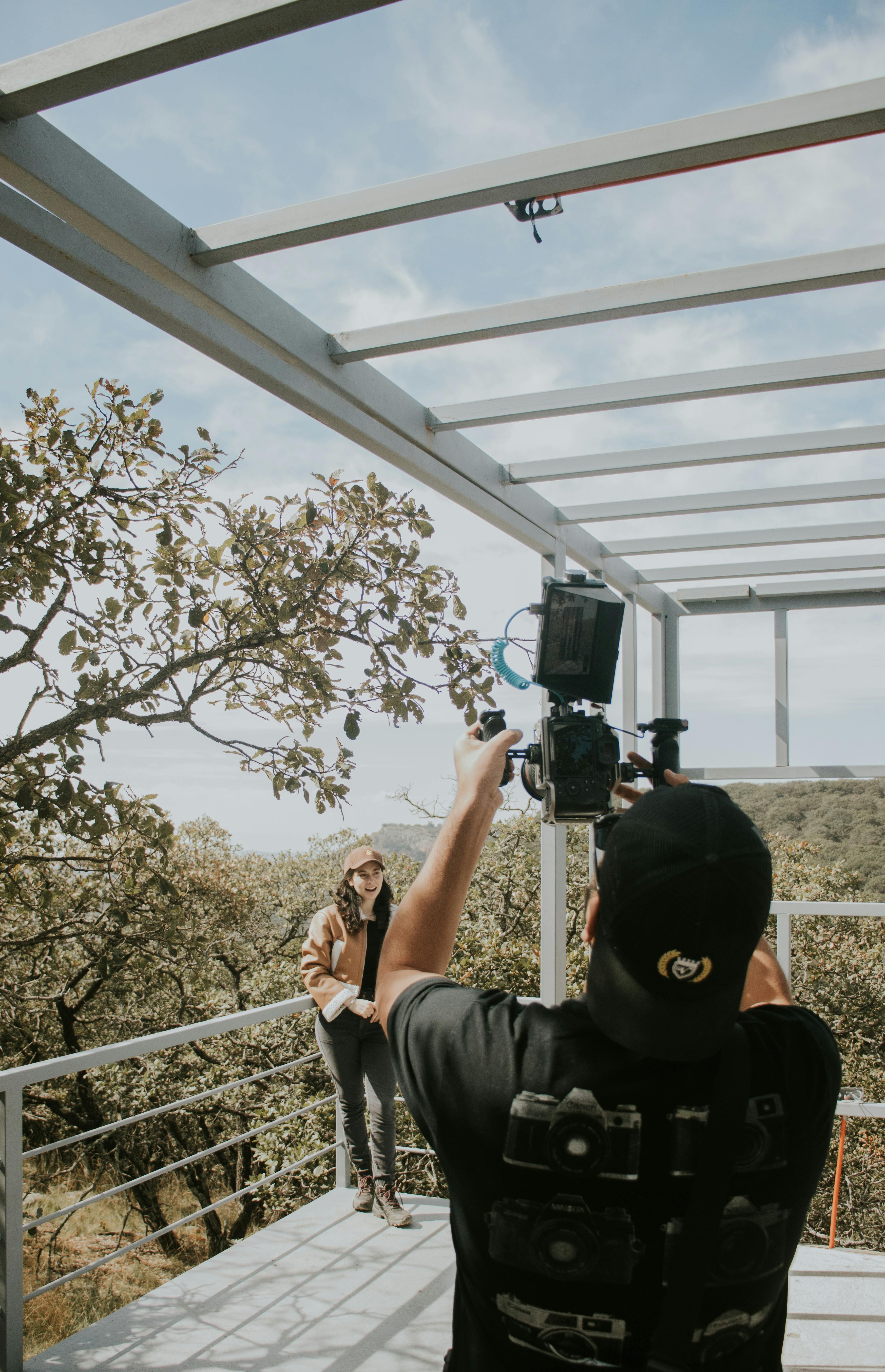 Photographer filming a woman in a scenic outdoor setting with natural light.