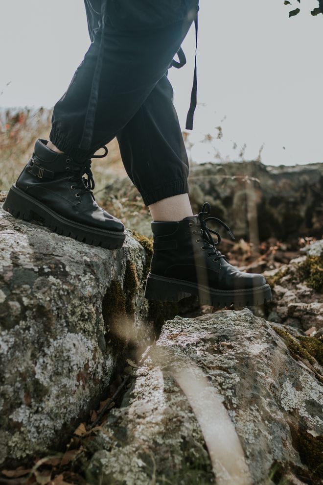 Walker stepping across wet rocks in dark trail boots — photo by Amar Preciado from Pexels