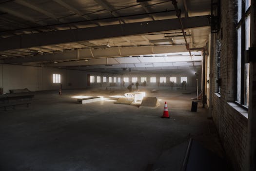Empty indoor skate park with ramps and natural light streaming in, perfect for skating.