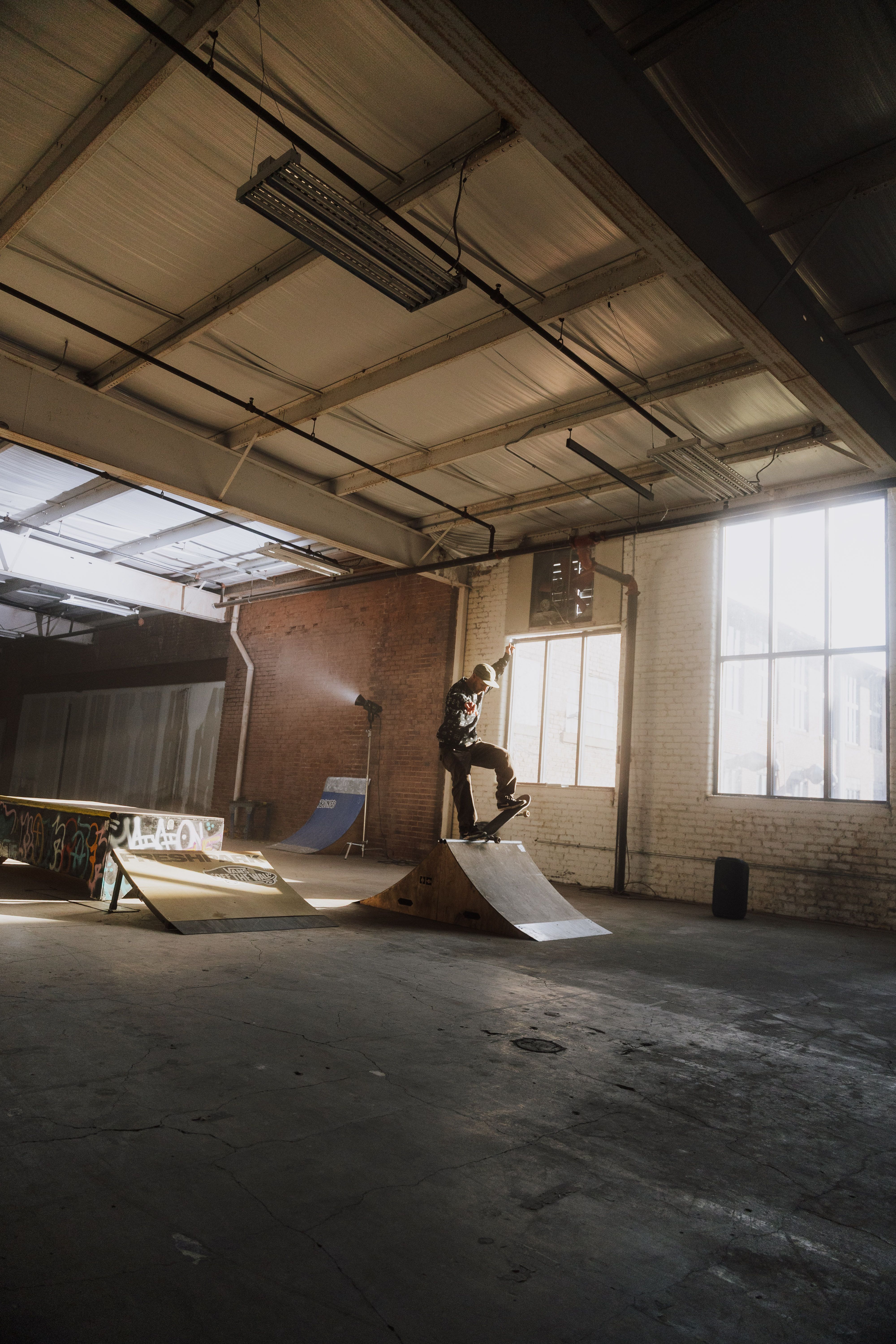 Skateboarder performing a trick indoors with dramatic lighting.