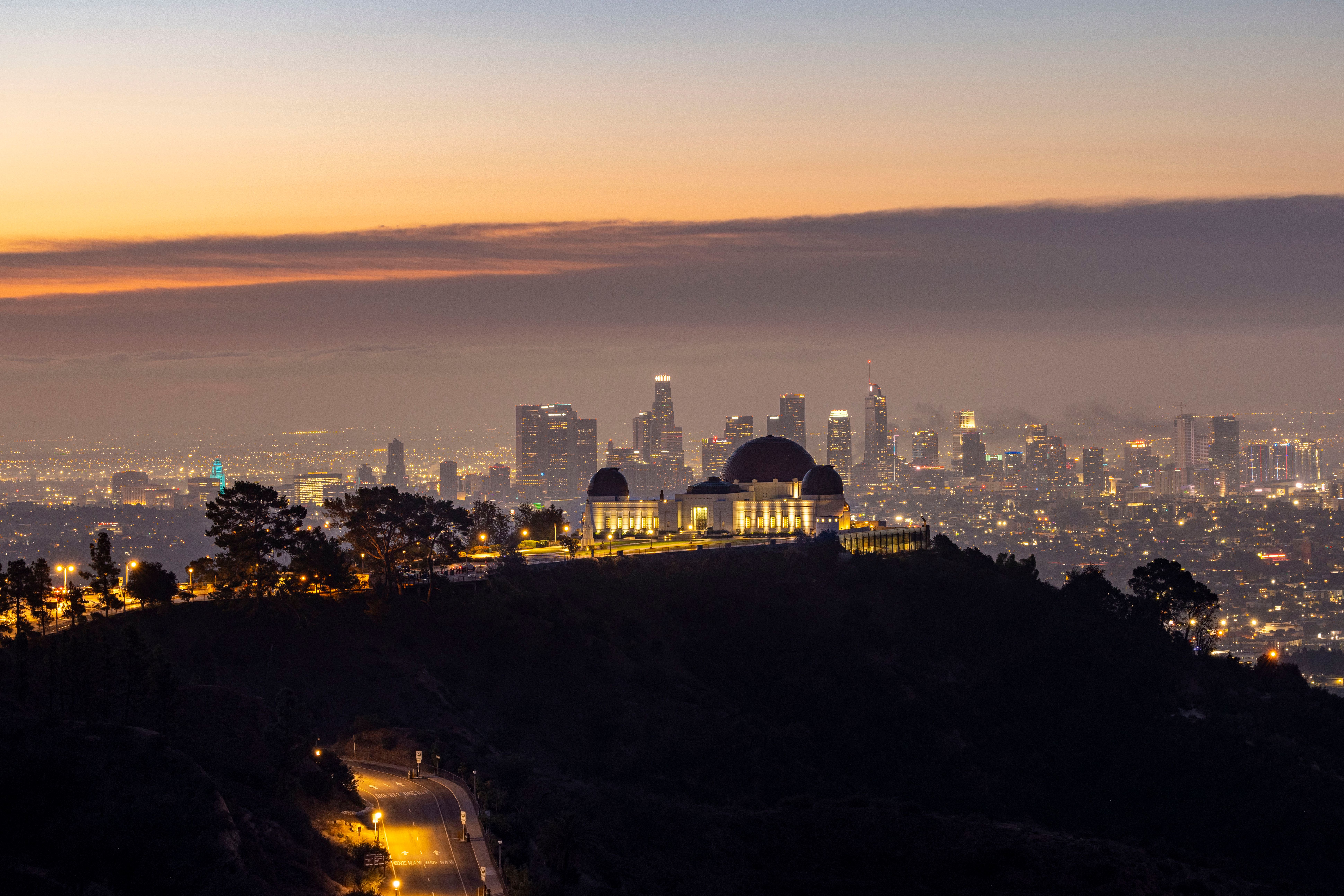 Exotic supercar parked outside a luxury Hollywood Hills mansion overlooking the Los Angeles skyline