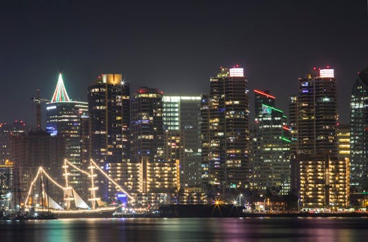 A stunning view of the San Diego skyline at night featuring a beautifully lit ship in the foreground.