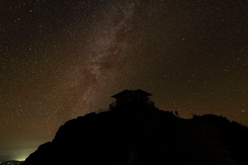 Free Silhouette of a mountain hut under a starry night sky, showcasing the Milky Way. Stock Photo