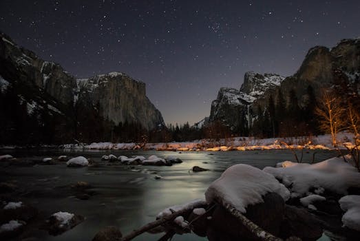 Stunning view of Yosemite Valley under a starry night sky with snow-covered landscape.