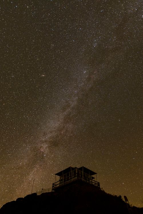 Free A silhouette of a lookout against the vibrant starry night sky and the Milky Way. Stock Photo