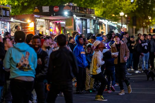 A lively crowd gathers around vibrant food trucks at night, enjoying a bustling street food experience.