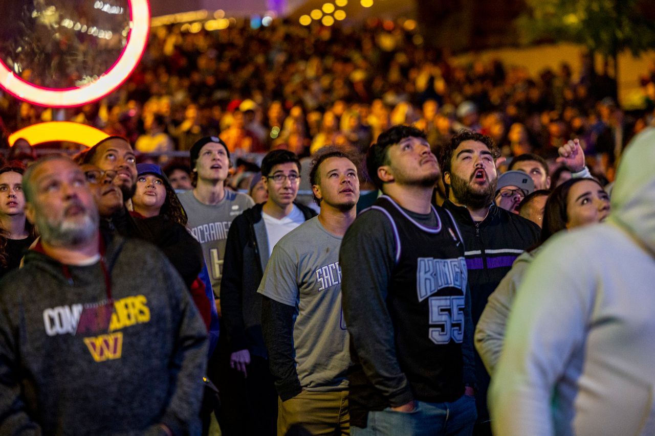a diverse crowd gathers at night watching a sports event with rapt att