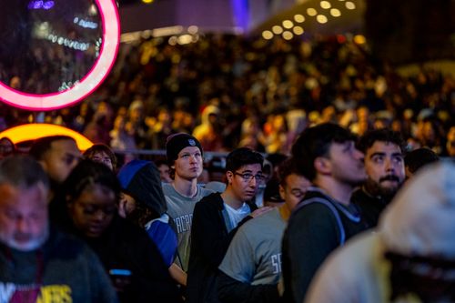 Free A diverse crowd gathers at a vibrant nighttime event, illuminated by neon lights. Stock Photo