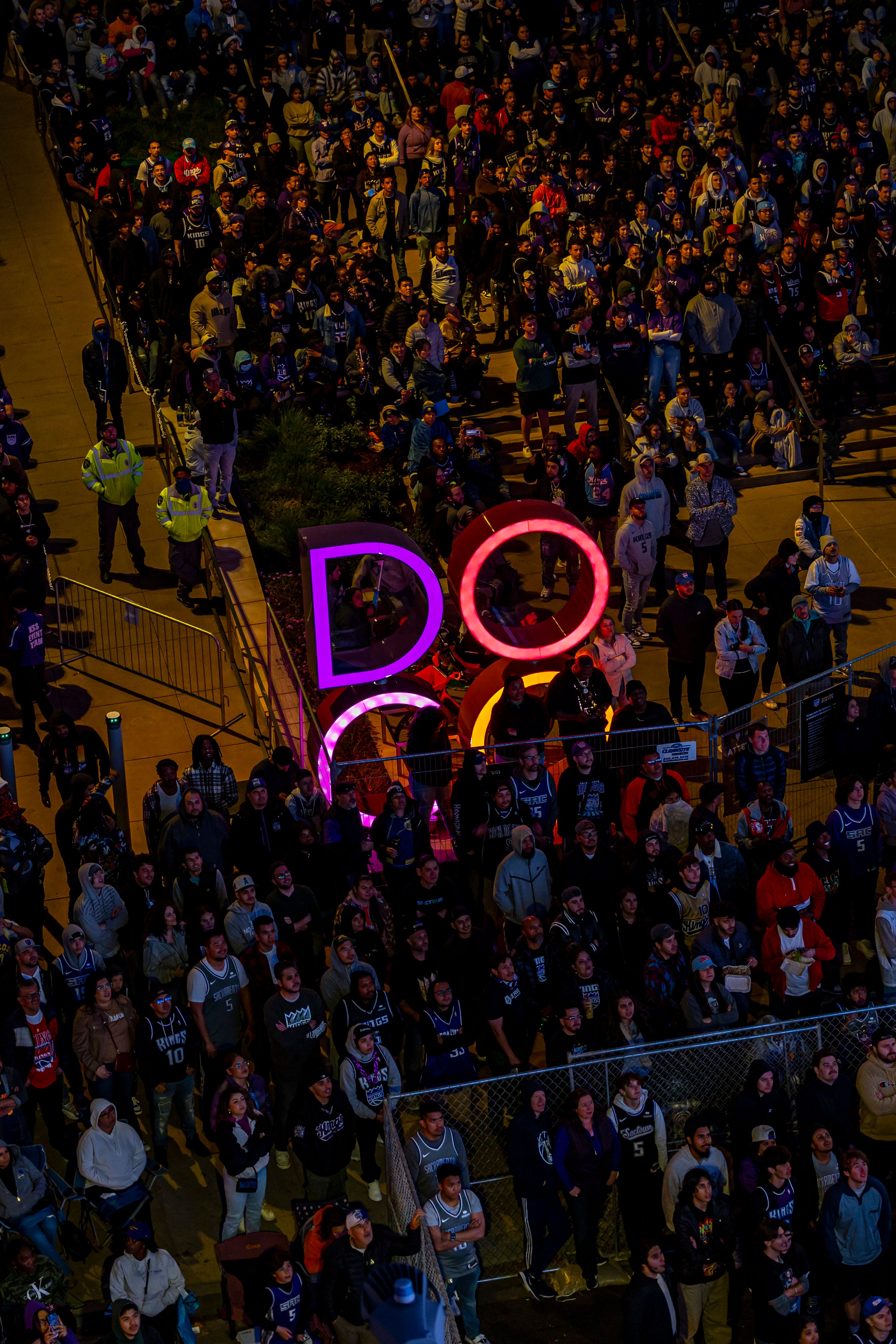 A vibrant night scene with a crowd and neon 'DOG' sign creating a lively atmosphere.