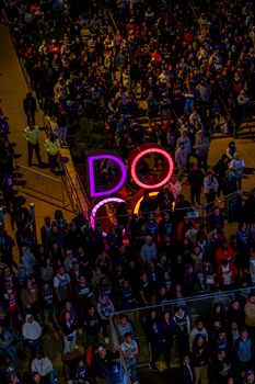 A vibrant night scene with a crowd and neon 'DOG' sign creating a lively atmosphere.