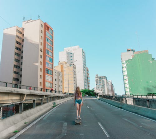 Faceless woman on skateboard riding along city asphalt road