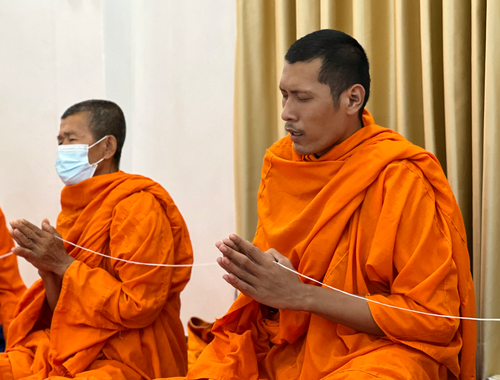 Free Buddhist monks in orange robes pray during a traditional Thai ceremony in Uttaradit, Thailand. Stock Photo