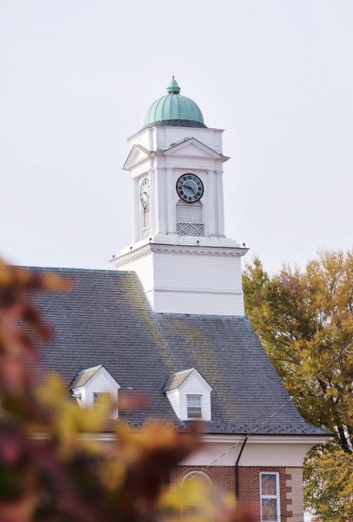 Free A classic clock tower on a historic building surrounded by autumn trees. Stock Photo