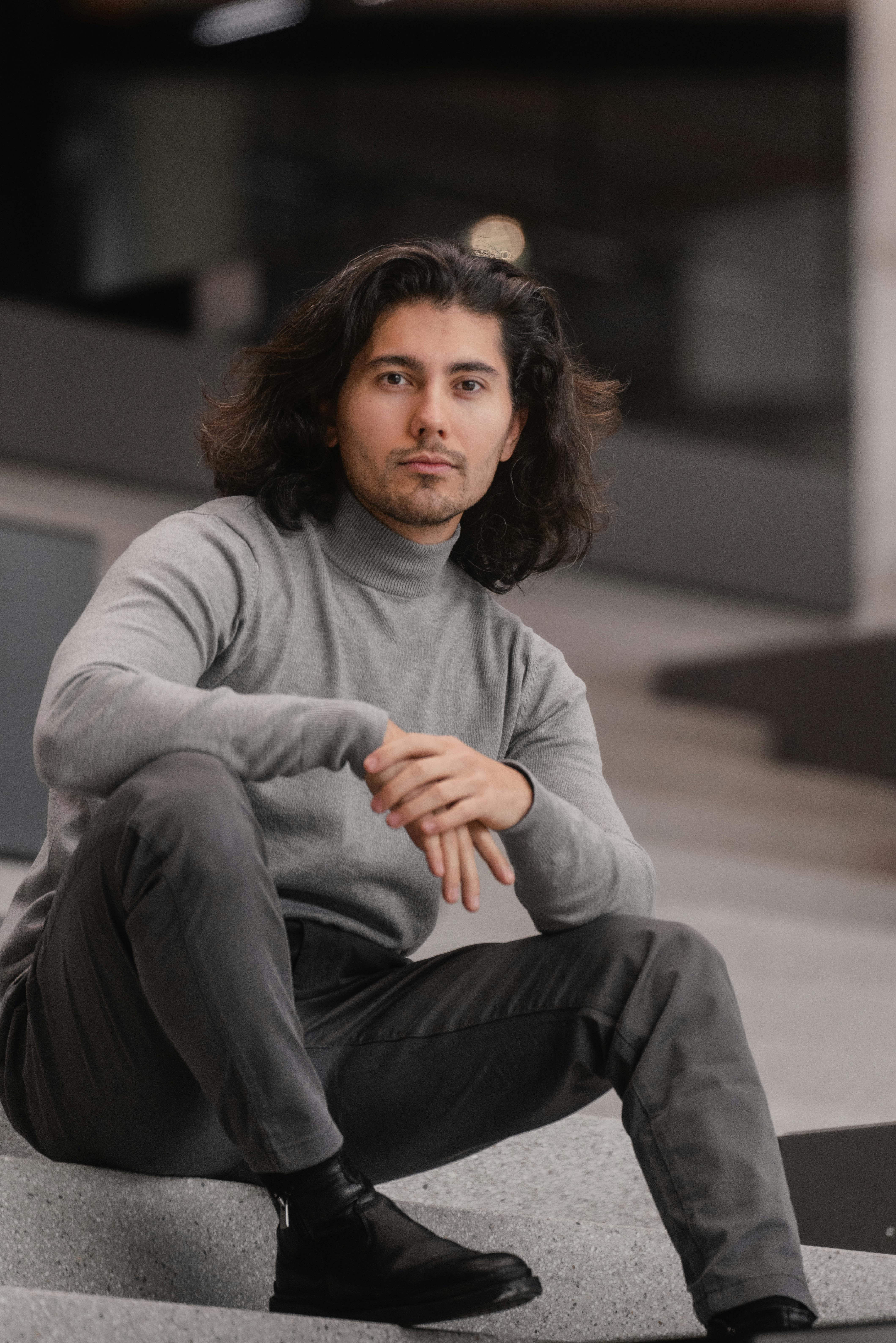 무료 현대적인 도시적 분위기 속에서 앉아 캐주얼한 패션 스타일을 선보이는 세련된 남자. 스톡 사진