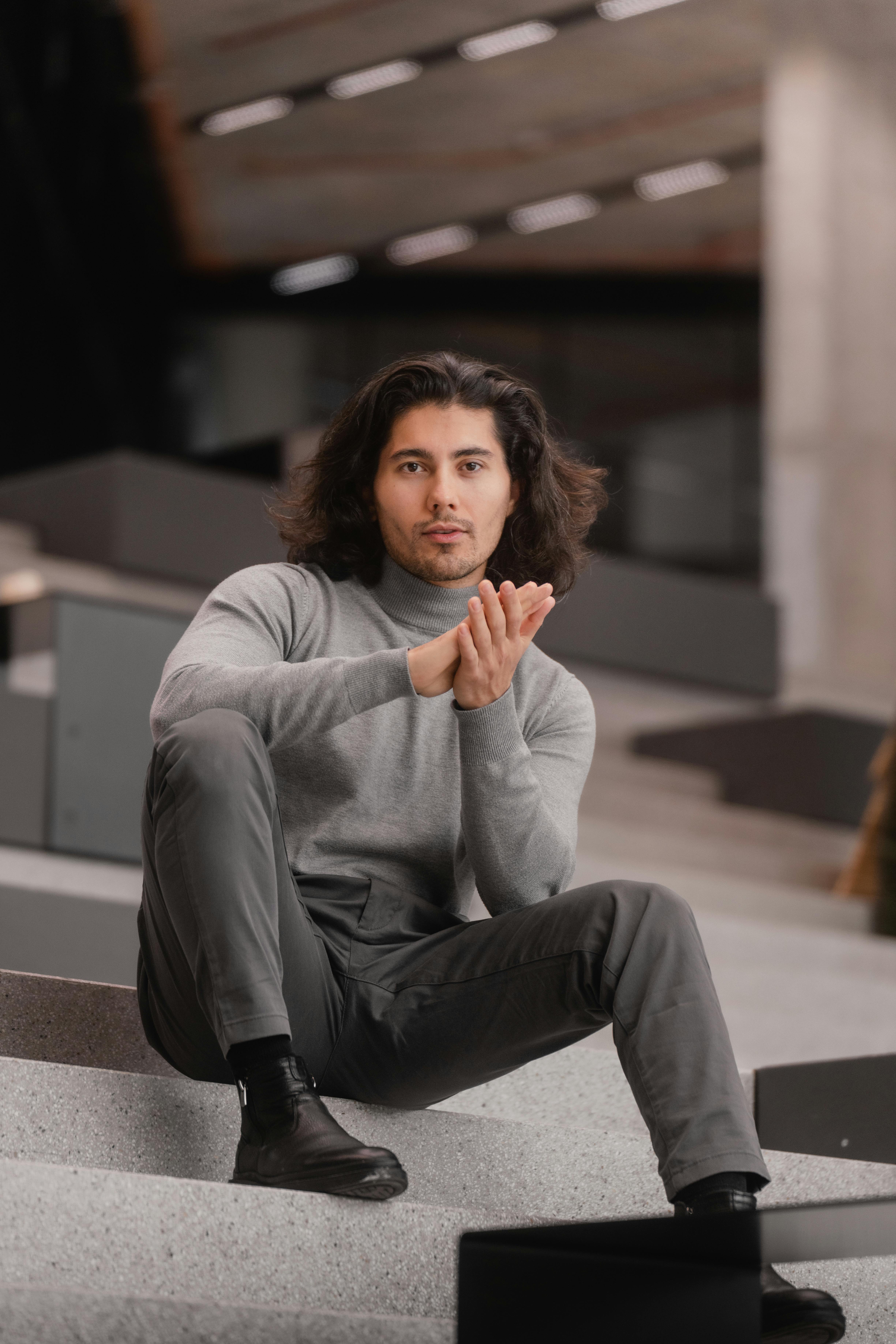 De franc Un home modern amb un vestit gris posant a les escales urbanes, mostrant un estil modern. Foto d'estoc