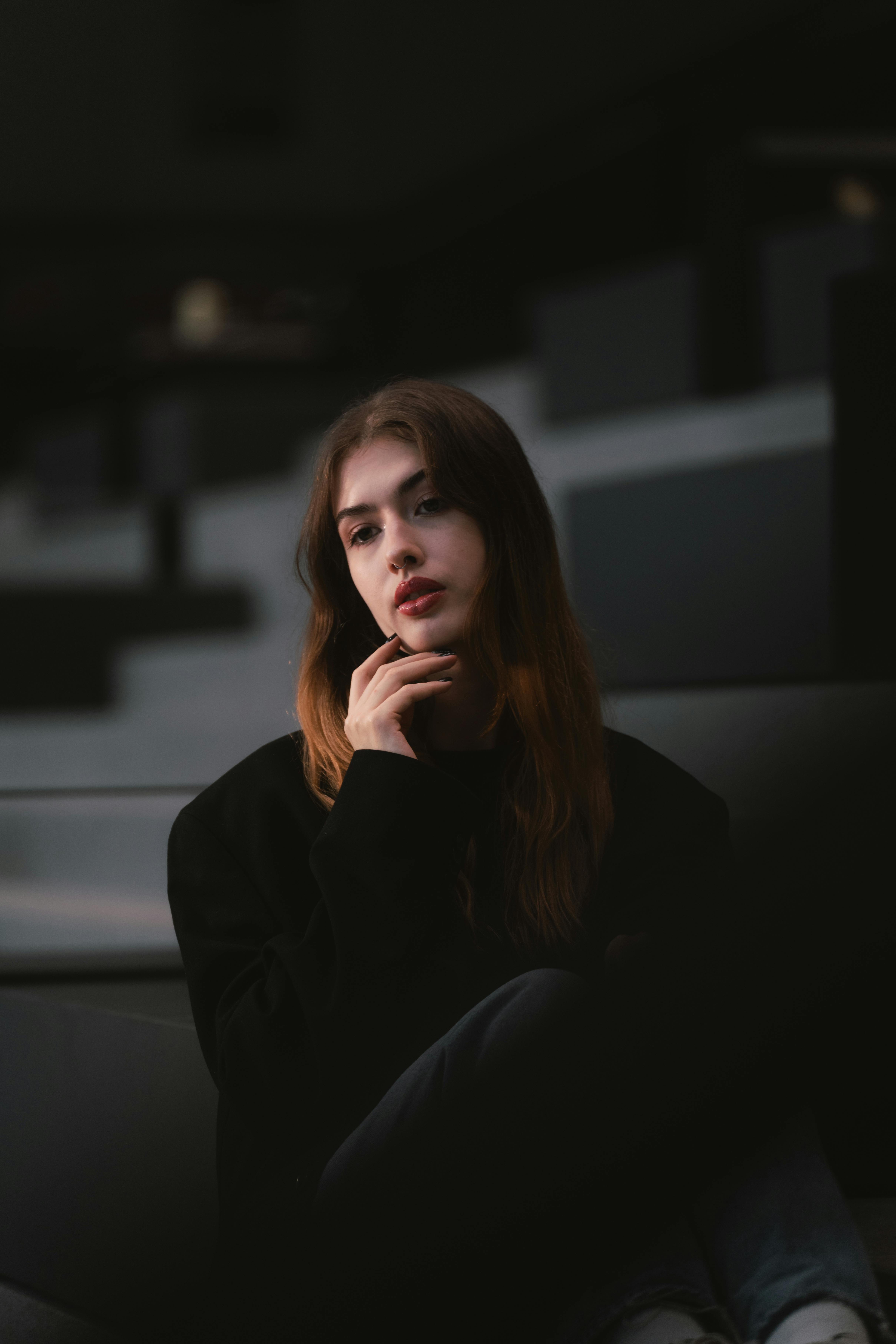 Gratuit Portret sumbru al unei tinere femei adulte așezate gânditoare într-un mediu urban. Fotografie de stoc