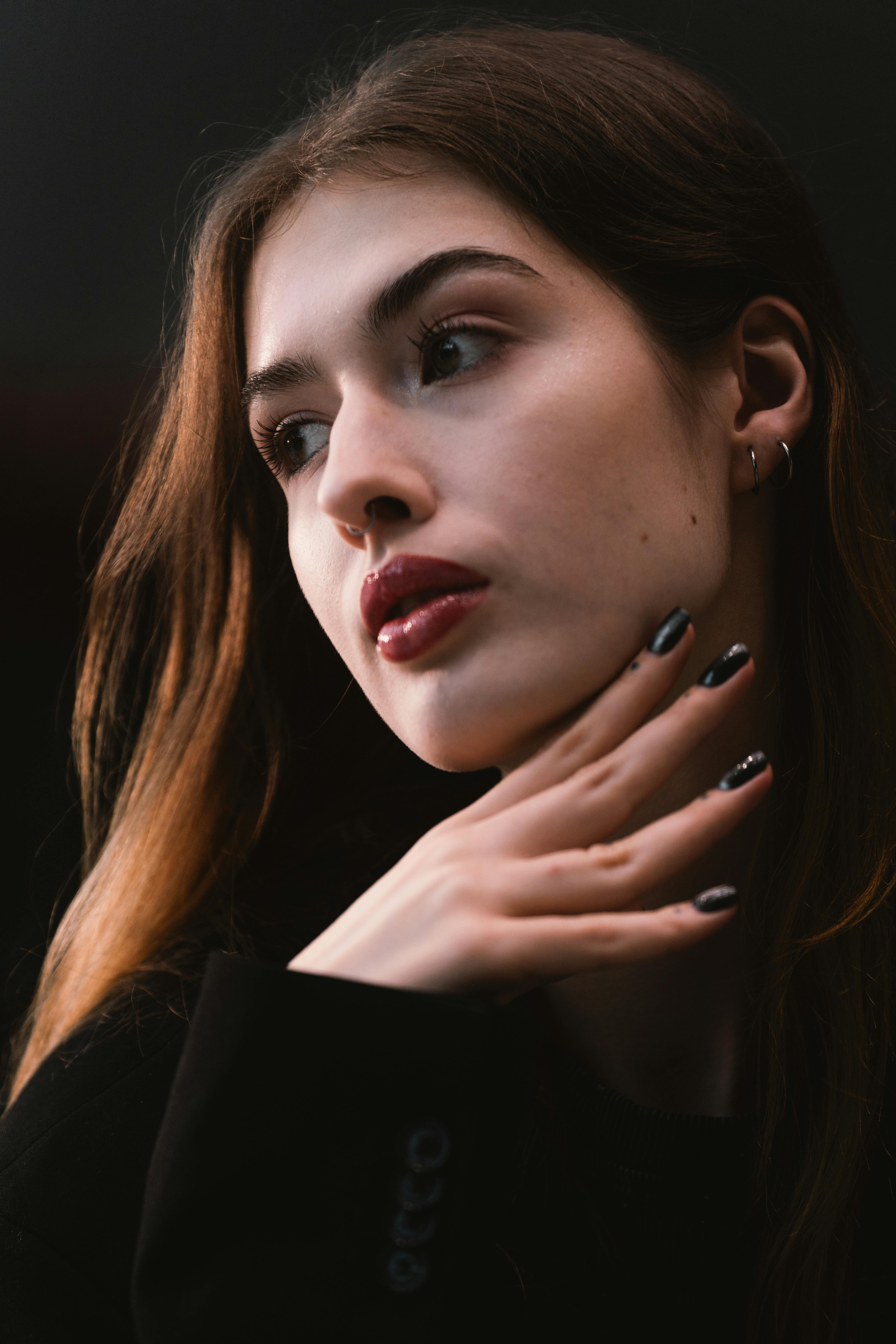 Miễn phí Một bức chân dung đầy phong cách của một phụ nữ trẻ với mái tóc và móng tay đen, được chụp trong tư thế đầy suy tư. Ảnh lưu trữ