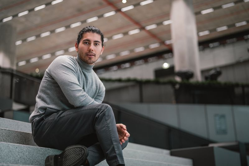 Portrait of a man sitting stylishly in a modern urban building in Vienna.
