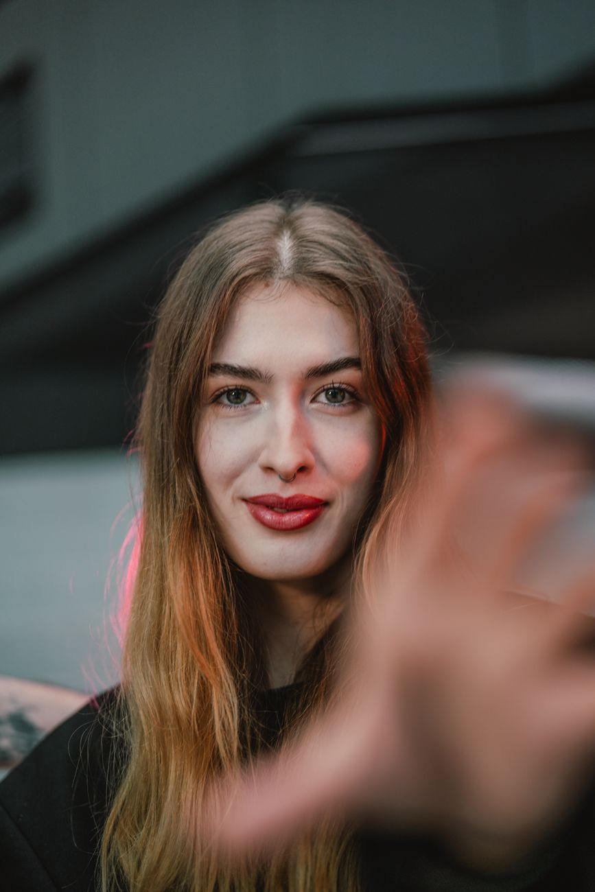 Close-up portrait of a young woman with a soft smile, captured in an urban environment.