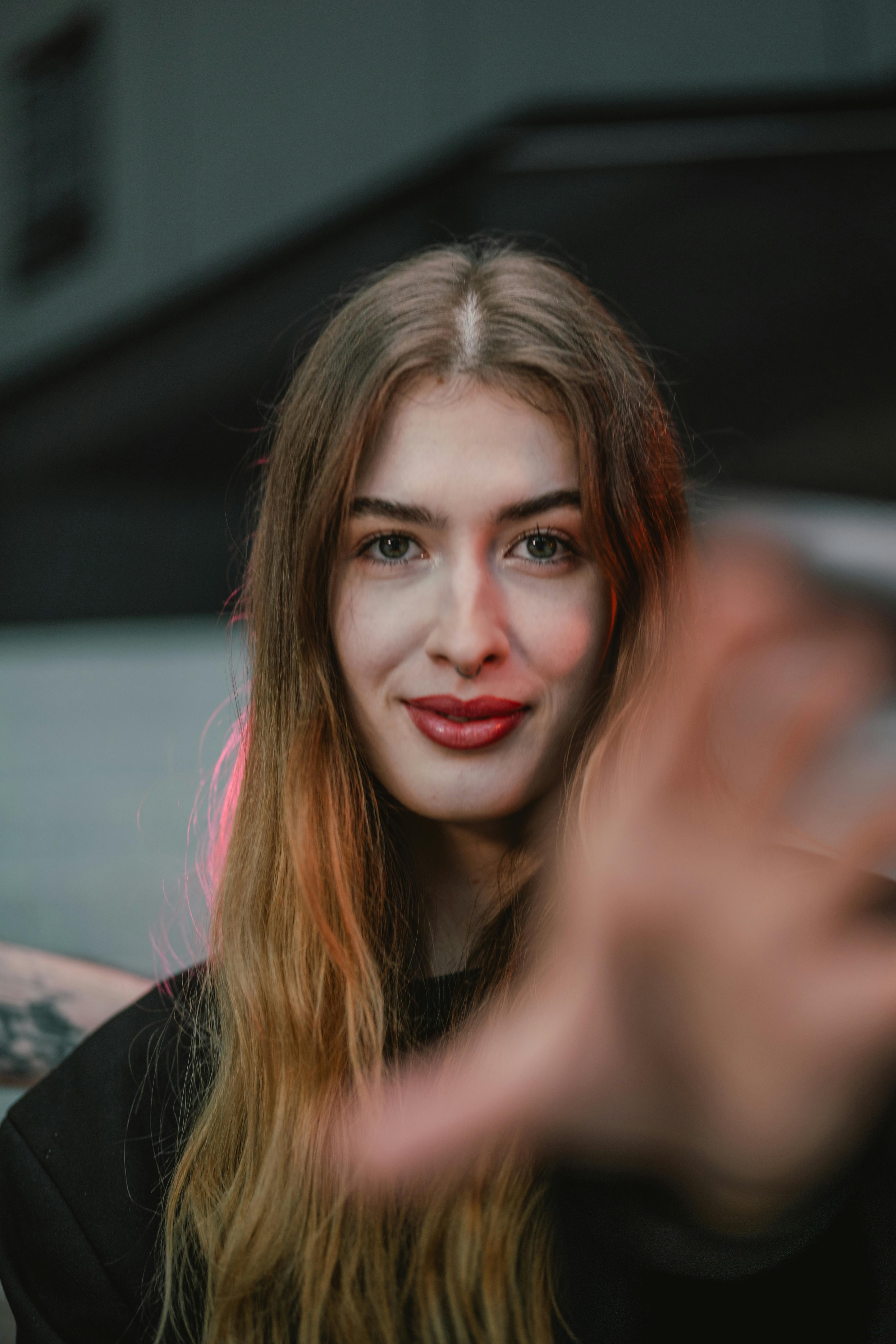 bezplatná Portrét mladé ženy, která se s vřelým úsměvem natahuje k ruce, zachycený venku ve Vídni. Základová fotografie