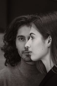 A striking black and white portrait of a man and woman showcasing modern fashion and emotional depth.