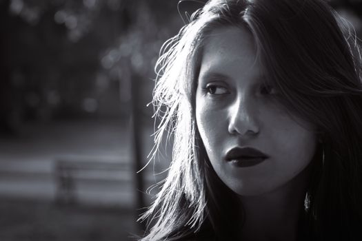 Evocative black and white portrait of a woman in a Graz park during fall afternoon light.