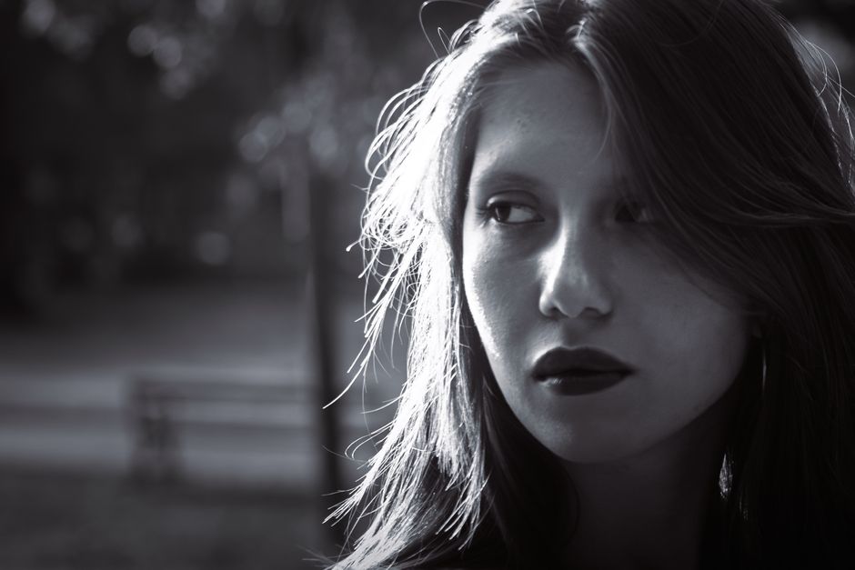 Evocative black and white portrait of a woman in a Graz park during fall afternoon light.