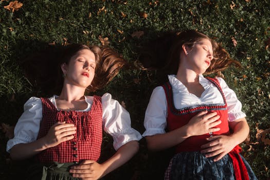 Two women in traditional European attire enjoying a peaceful moment in a grassy park in autumn.