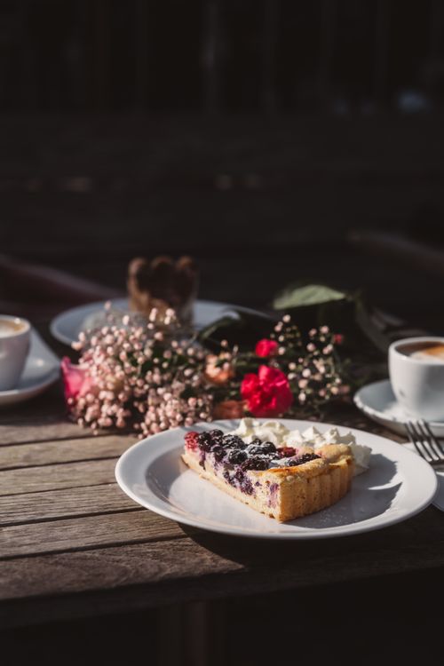 Free Delicious berry tart with cream served alongside coffee on a rustic outdoor table. Stock Photo