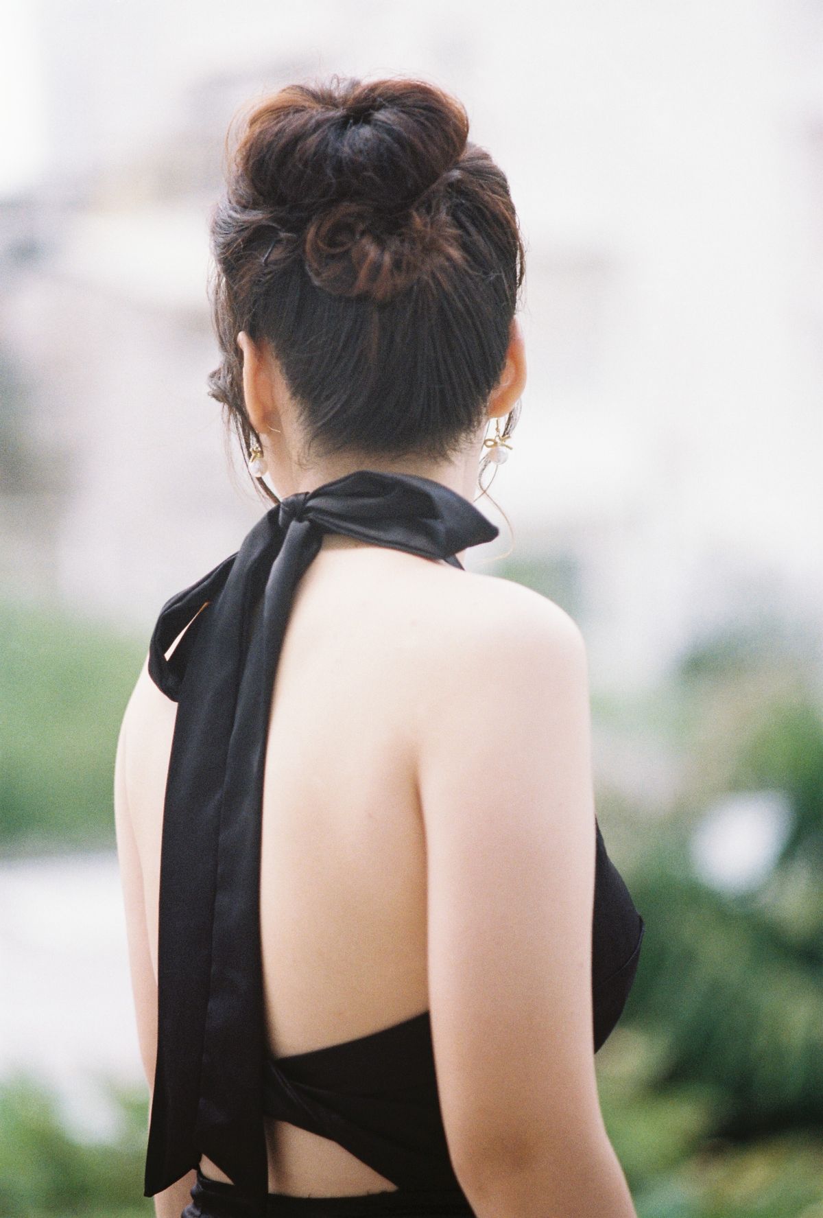 Woman with an elegant updo in a black dress posing outdoors