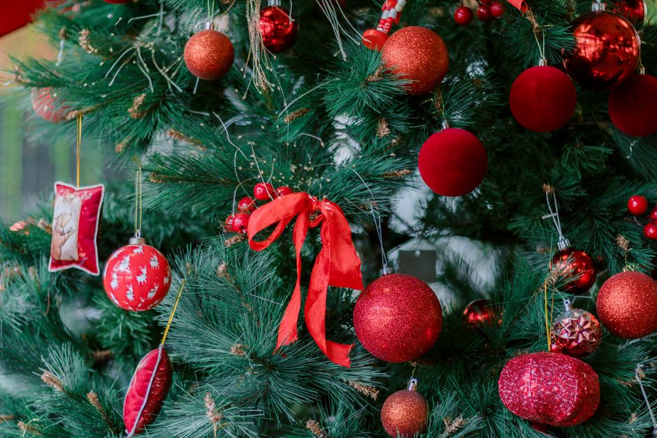 Close-up of a Christmas tree adorned with red ornaments and ribbons.