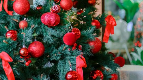 Free Close-up of a decorated Christmas tree with red ornaments and ribbons, creating a festive atmosphere. Stock Photo