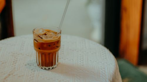 Free Glass of iced coffee with a straw on a lace-covered table. Stock Photo