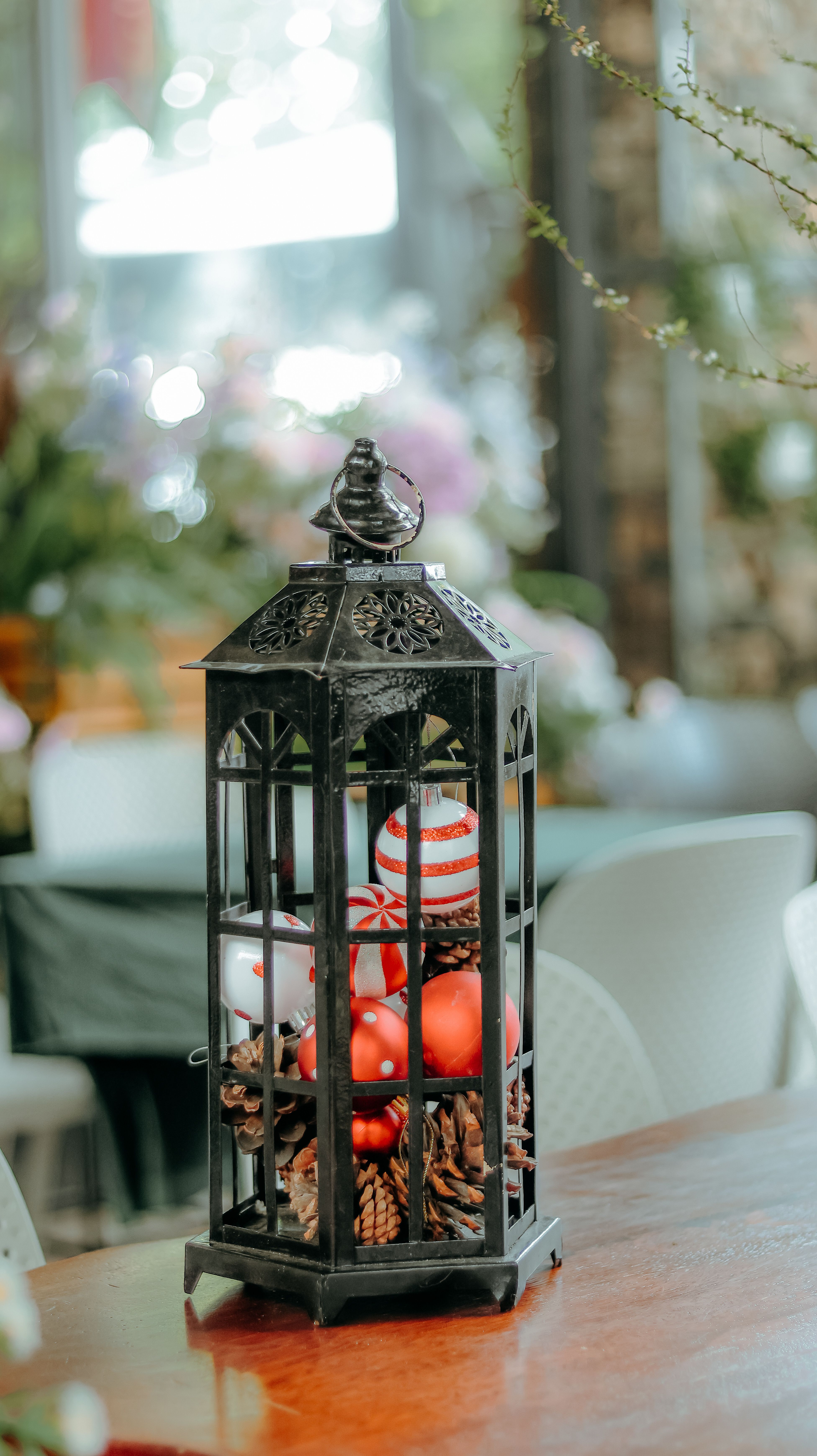 Rustic lantern filled with festive holiday ornaments on a wooden table.