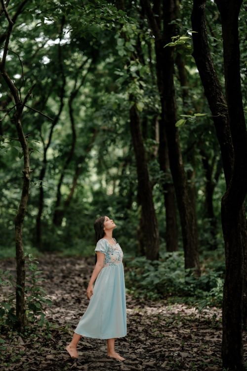 Free A serene moment captured of a woman in a blue dress enjoying a peaceful walk in a dense, green forest. Stock Photo