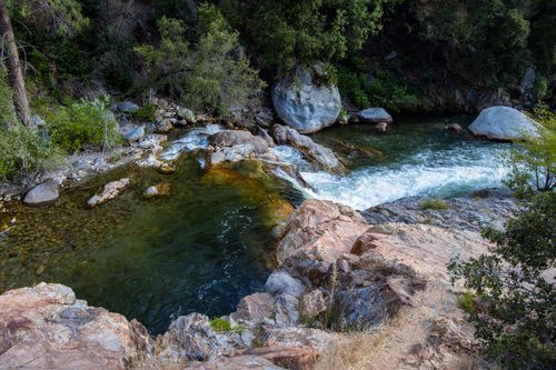 Free Scenic view of a tranquil river meandering through rocky terrain and lush greenery in California. Stock Photo