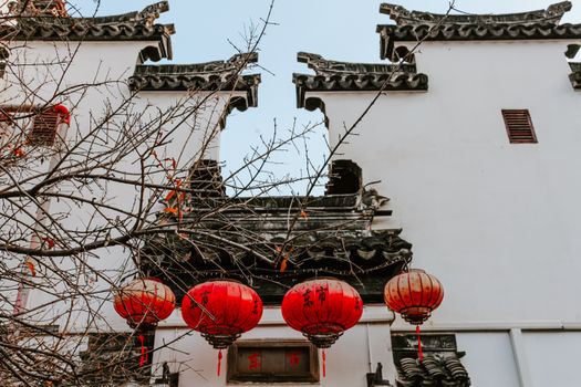A view of traditional Chinese architecture with red lanterns in Nanjing during autumn.