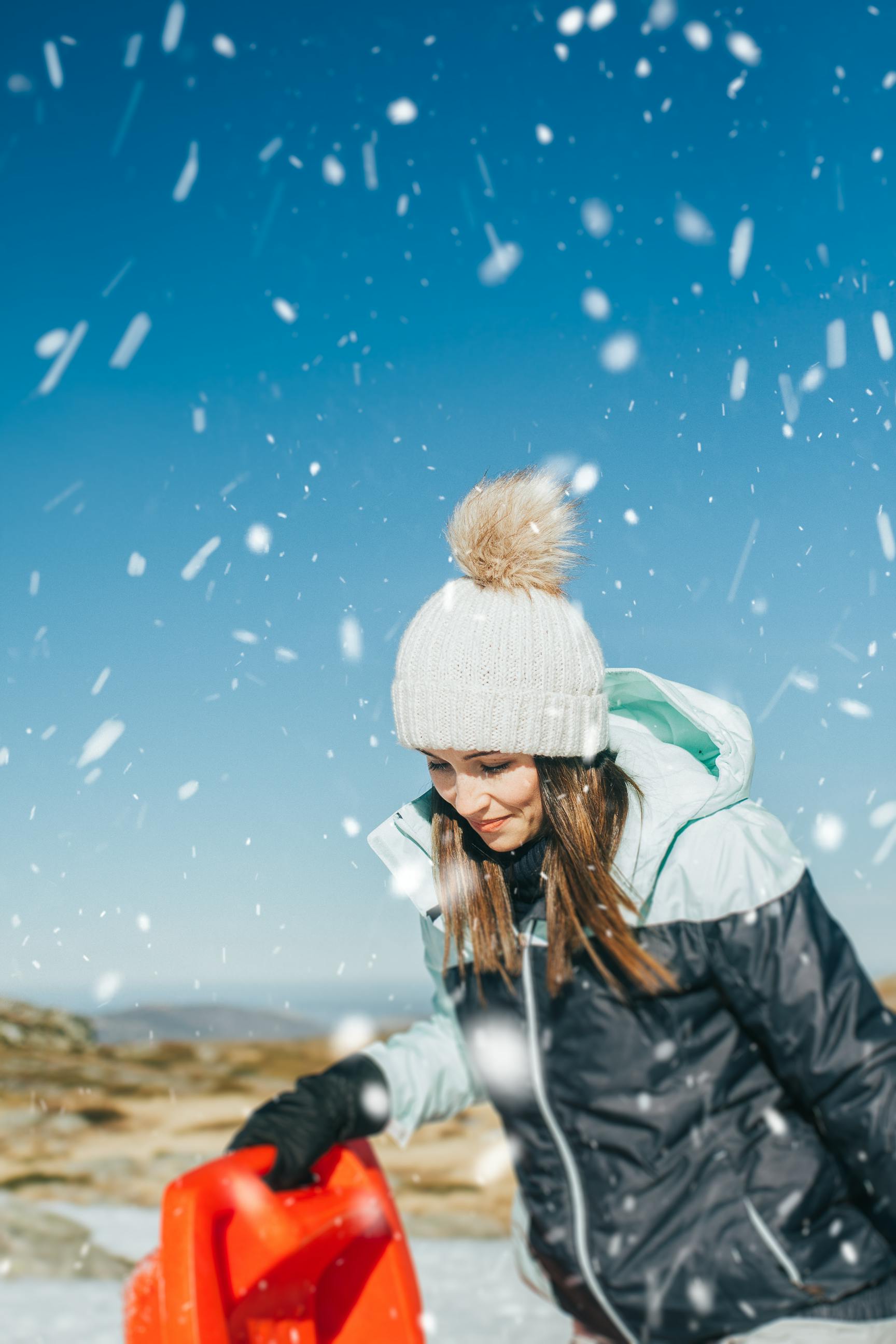 Woman enjoying a snowy day outdoors dressed in winter fashion with a beanie and jacket.