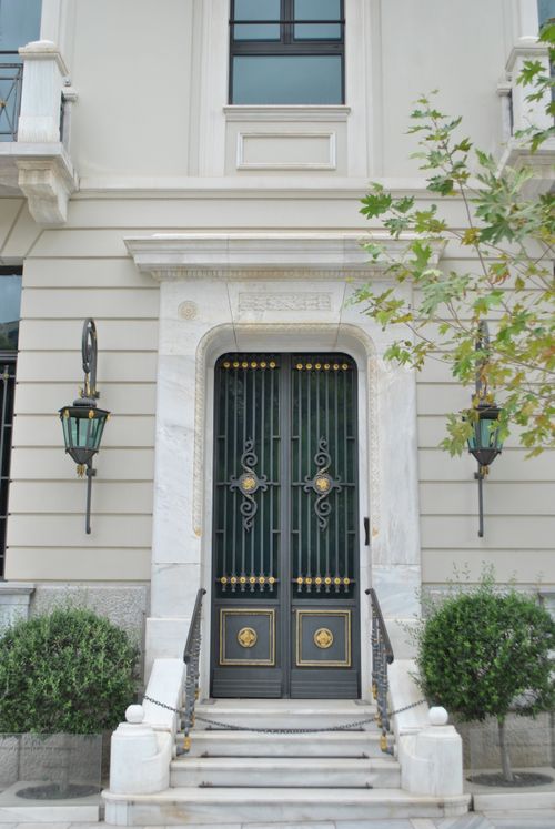 Free Elegant entrance with black iron doors, marble frame, and green lanterns. Stock Photo