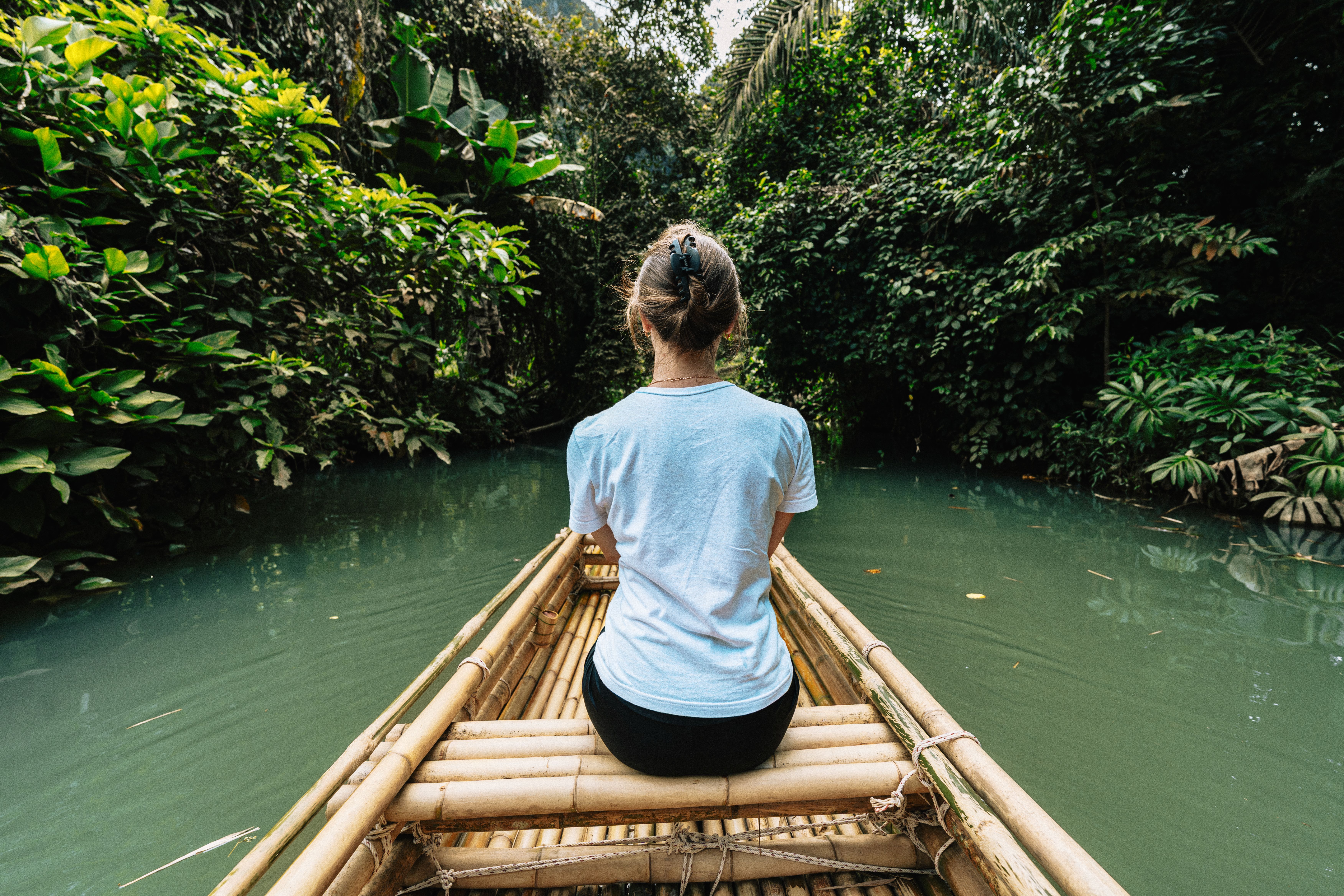 Femme sur une barque en bambou naviguant sur les canaux luxuriants de Krabi, en Thaïlande.