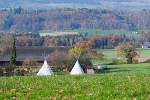 Free Idyllic Swiss landscape featuring teepees and rolling hills in a vibrant autumn setting. Stock Photo