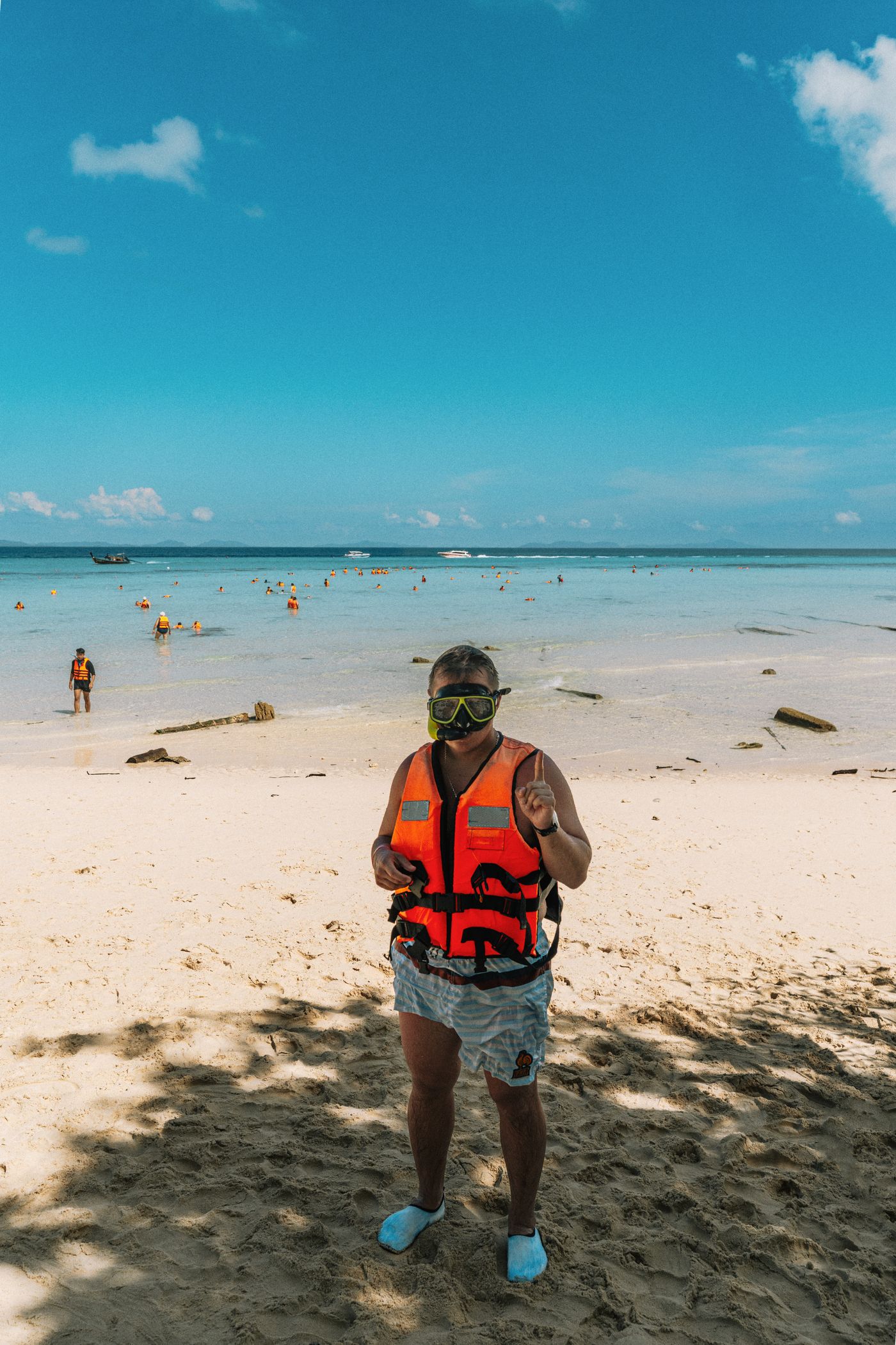 Snorkeler standing on a tropical beach in safety gear
