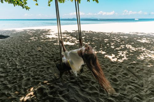 Free Young woman enjoying a swing on a tropical beach in Krabi, Thailand. Stock Photo