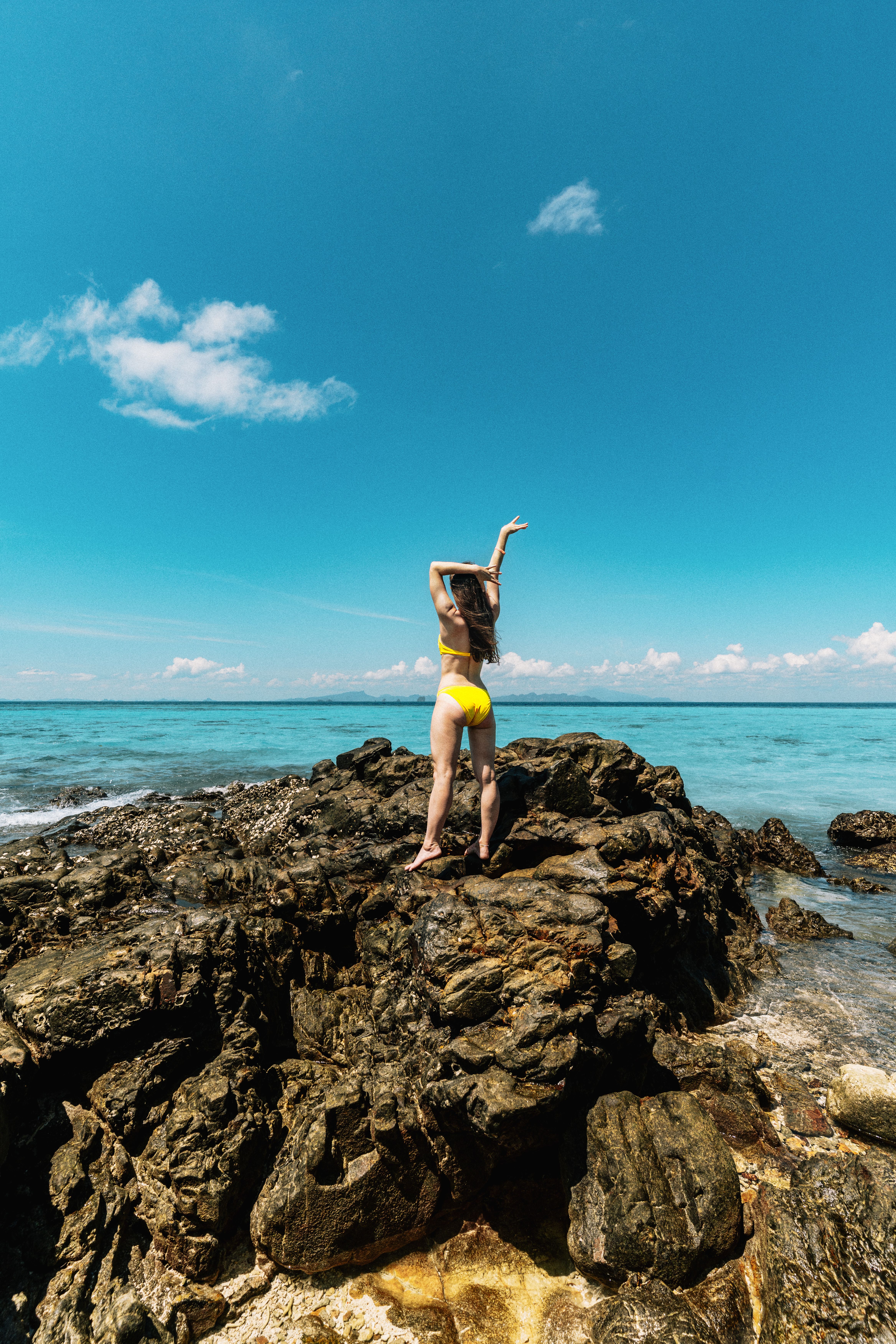woman-in-yellow-bikini-on-rocks-overlooking-sea-free-stock-photo