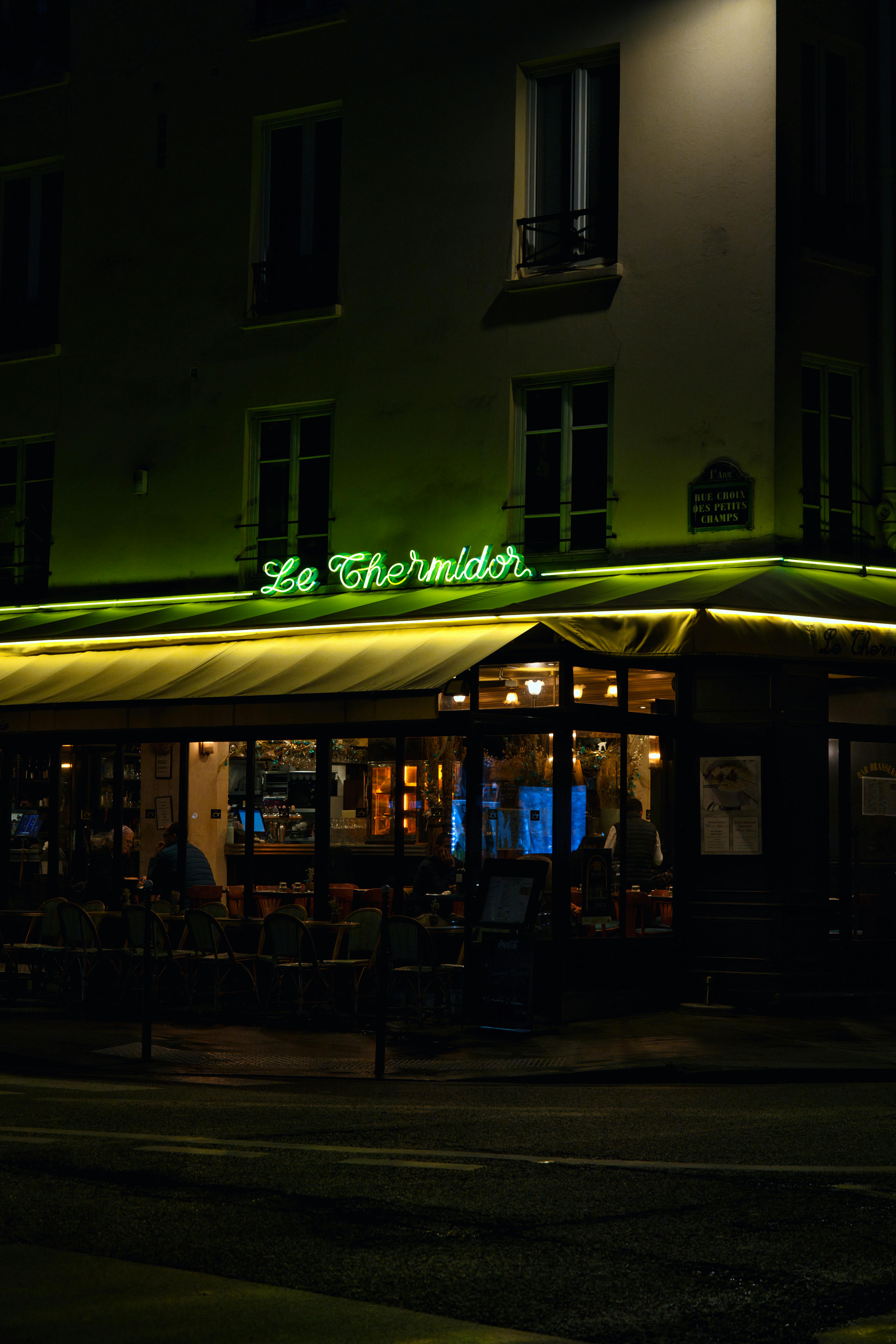 Enchanting night view of a cozy Parisian restaurant with neon lights.