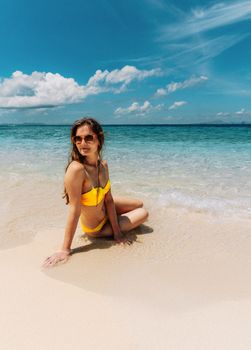 Young woman in yellow bikini enjoys sunny day at Ao Nang Beach, Thailand.