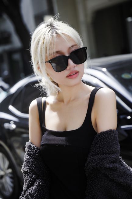 Fashionable woman in sunglasses poses confidently outdoors, showcasing modern urban style.